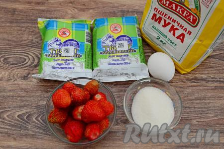 Подготовить продукты для приготовления сырников с клубникой в духовке. Творог лучше брать жирностью от 5% и выше. Клубнику можно взять как свежую, так и замороженную. Свежую клубнику нужно будет очистить от чашелистиков, промыть, а затем обсушить, разложив её на бумажном полотенце. Если у вас замороженная клубника и на ней нет наледи, тогда ягодки можно не размораживать.