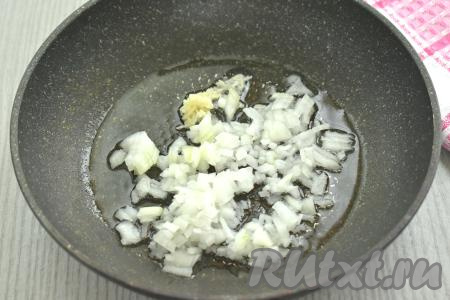В сковороде прогреваем растительное масло, выкладываем мелко нарезанный лук и пропущенный через пресс зубчик чеснока, перемешиваем, обжариваем на среднем огне до золотистости лука (ориентировочно в течение 3-4 минут), не забывая периодически перемешивать.