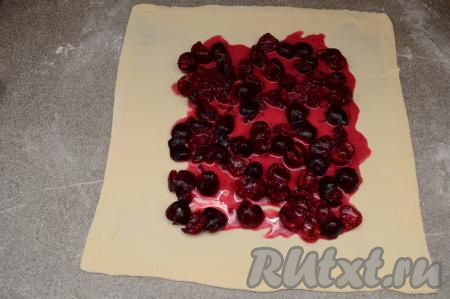 На раскатанный пласт теста выложить начинку из черешни, отступив по 3-4 сантиметра от краёв теста.