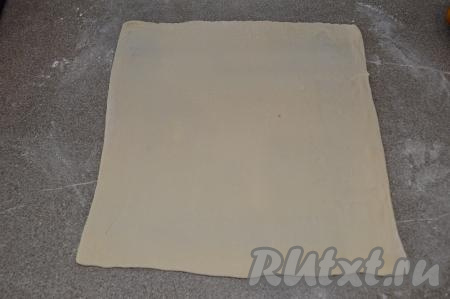 Присыпать рабочую поверхность слегка мукой. Выложить разморозившееся слоёное тесто и раскатать его в пласт толщиной 2-3 миллиметра. В результате у меня получился квадрат со стороной 33 сантиметра.