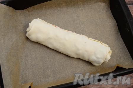 Прищепить край теста, чтобы начинка не вытекала при выпечке штруделя. Аккуратно выложить штрудель на противень, застеленный пергаментом.&nbsp;