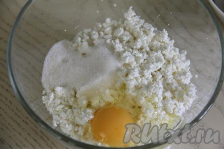 В достаточно глубокую миску выложить творог, всыпать сахар, добавить сырое яйцо. Перемешать творожную массу вилкой (или столовой ложкой, или лопаткой) до однородности.