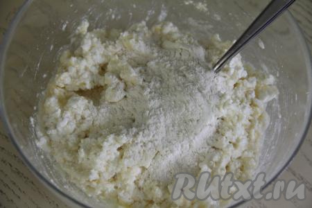 Перемешать творожную массу вилкой до однородности. Начать постепенно, по половине столовой ложки, всыпать муку в творожную массу, каждый раз полностью вмешивая её в тесто.