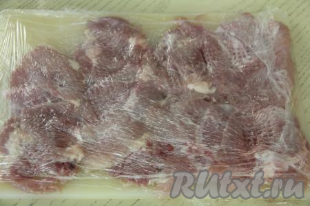 Выложить филе бёдер на разделочную доску, накрыть пищевой пленкой. Отбить мясо с двух сторон с помощью кулинарного молоточка до толщины ориентировочно 7 миллиметров.