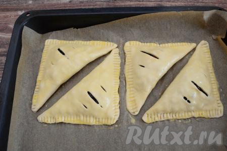 В небольшую ёмкость выложить яичный желток, взболтать его вилкой до однородности. Смазать взбитым желтком поверхность каждой слойки. Выпекать слойки с жимолостью в разогретой до 200 градусов духовке минут 20-25 (до подрумянивания слоёного теста).