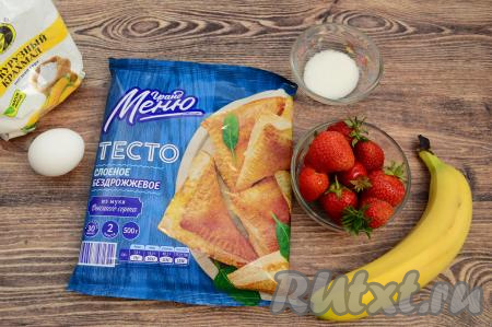 Подготовить продукты для приготовления слоек с клубникой и бананом. Банан для этих слоек лучше брать небольшой, спелый или даже переспелый. Слоёное тесто можно взять как дрожжевое, так и бездрожжевое. У меня в этот раз было бездрожжевое слоёное тесто. Заранее достать слоёное тесто из морозилки, чтобы оно разморозилось и стало достаточно мягким. Со свежей клубникой эти слойки получаются более аппетитными, но при желании можно использовать и замороженные ягоды (их нужно будет разморозить совсем немного, чтобы можно было нарезать на части). Свежую клубнику нужно будет отделить от чашелистиков, промыть водой, дать немного обсохнуть.