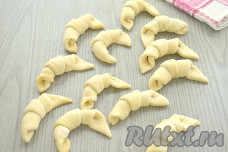 Каждый треугольник, начиная с края с изюмом, сворачиваем в рогалик. "Хвостик" теста (то есть край треугольника) должен быть снизу.