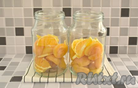 Половинки абрикосов и ломтики апельсина равномерно распределяем по двум простерилизованным банкам объёмом по 1 литру.