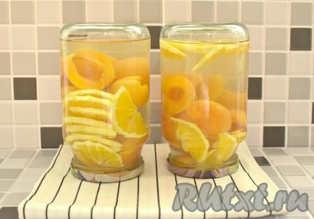 Снимаем сироп с огня и сразу разливаем его по банкам с абрикосами и апельсинами, заполняя баночки до самого верха. Банки с компотом закручиваем (или закатываем) крышками. Проверяем банки на герметичность, для этого кладём их на бок и прокатываем по столу. Банки с компотом ставим дном вверх, укутываем в плед (или одеяло), оставляем до полного остывания (ориентировочно на сутки).