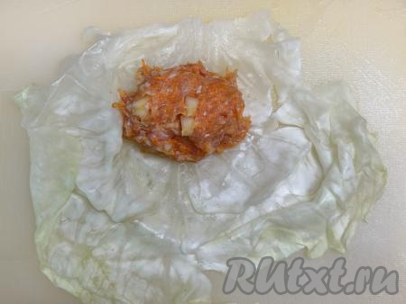 Начинку разделить на 7 частей (по количеству подготовленных капустных листьев). На подготовленный лист капусты ближе к утолщённому краю листа выложить одну часть начинки, подвернуть вначале утолщённую часть листа на начинку.&nbsp;