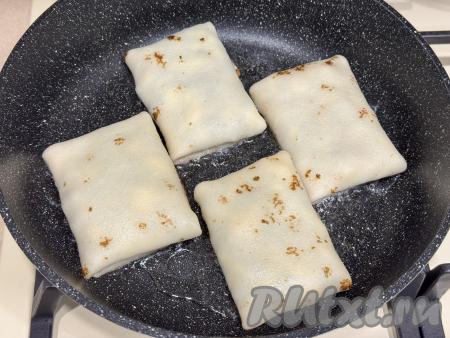 В сковороду влить растительное масло, разогреть, выложить блины с начинкой.&nbsp;