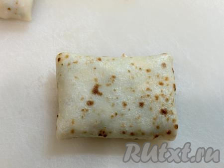 И, начиная со стороны с луково-яичной начинкой, завернуть блин в прямоугольный конвертик.&nbsp;