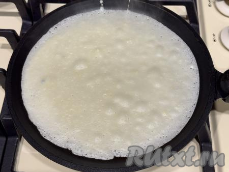 После того как тесто настоится в течение 10-15 минут, можно приступать к жарке блинов. Для этого нужно на достаточно сильном огне хорошо разогреть сковороду (у меня сковородка диаметром 20 сантиметров), смазанную растительным маслом, влить половник теста. Равномерно распределить тесто по дну сковородки.