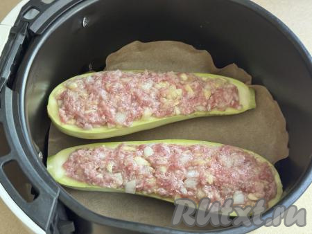 Дно чаши аэрогриля застелить пергаментом, затем выложить две кабачковые лодочки с мясной начинкой, крышку закрыть.