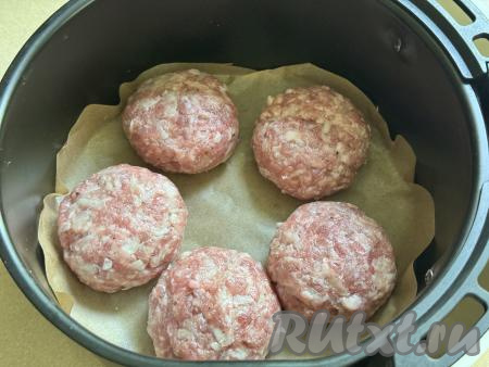 Чашу аэрогриля застелить пергаментом. Из каждой части фарша из свинины сформировать круглую котлету, выложить в чашу аэрогриля.&nbsp;