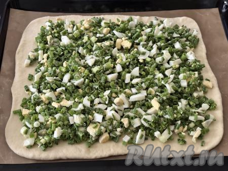 Переложить коврик (или бумагу) с тестом на противень. Поверх раскатанного теста, отступая от краёв по 1-1,5 сантиметра, равномерно выложить начинку из лука и яиц.&nbsp;