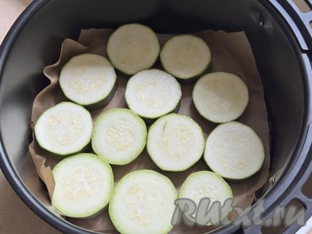Дно чаши аэрогриля застелить пергаментом, выложить кружочки кабачка.