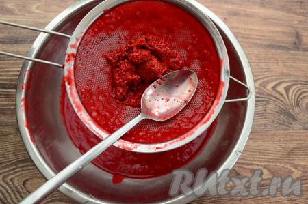 Взять вторую миску, поверх неё поставить сито. С помощью столовой ложки протереть через сито в миску малиновое пюре. В миске у нас будет находиться однородное процеженное малиновое пюре. А в сите останутся косточки (они нам не понадобятся). Протирается малиновое пюре через сито и просто, и быстро (я перетирала 5 минут), а в результате замороженная масса получится однородной и очень нежной. 