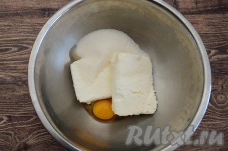 В миску выложить творог, вбить сырое яйцо, сразу же всыпать сахар.