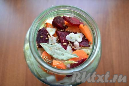 Далее снова выложить часть капусты, морковки и свеклы, лавровый лист, немного кориандра, горчицы и чеснока. Таким образом наполнить банку доверху, утрамбовывая содержимое.