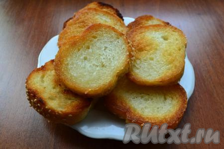 Ломти батона обжарить с одной стороны до румяности, переложить на тарелку, дать остыть. Постепенно обжарить с одной стороны все ломти батона, дать остыть.
