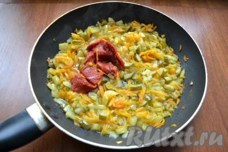 Перемешать овощи и обжарить их, иногда помешивая, до мягкости моркови (ориентировочно на жарку потребуется минут 5-6). Затем добавить солёные огурцы, обжаривать овощи вместе минут 5-7, периодически перемешивая. Добавить томатную пасту, влить огуречный рассол.