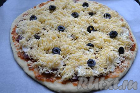 Щедро посыпать все натертым на средней терке сыром. Сверху сыра разложить маслины, нарезанные кружочками.