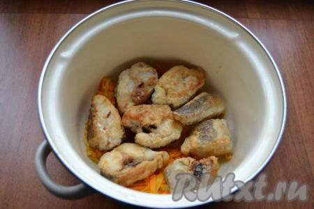 Кусочки хека обвалять в муке со всех сторон, затем выложить на отдельную сковороду, уже разогретую с растительным маслом. Обжарить кусочки хека&nbsp;на среднем огне до румяности&nbsp;с двух сторон. Далее половину обжаренных овощей выложить на дно кастрюли с толстым дном, на овощи разложить обжаренные кусочки хека.