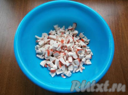 Рис всыпать в сито, промыть под проточной водой, затем выложить в кастрюлю с кипящей подсоленной водой, перемешать, дать воде закипеть, варить до готовности (минут 20-25) на небольшом огне. Сварившийся рис откинуть на сито, чтобы стекла вода, дать остыть. Яйца отварить в течение 10 минут после начала кипения воды, а затем остудить их и очистить. Крабовые палочки разморозить, вынуть из упаковки, нарезать на кружочки (или полукружочки), выложить в миску.