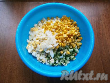 В салат из крабовых палочек, огурца и яиц добавить консервированную кукурузу без жидкости, мелко и тонко нарезанный очищенный репчатый лук.