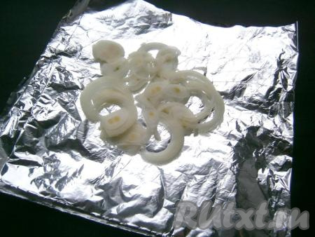 На лист фольги, сложенный вдвое, выложить очищенный и нарезанный тонкими полукольцами (или кольцами) репчатый лук.