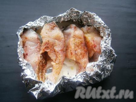 Стейки толстолобика выложить на лук. Края фольги подвернуть вовнутрь, формируя формочку для запекания с открытым верхом. Сбрызнуть рыбу растительным маслом. Далее поместить в разогретую до 180 градусов духовку на 30-35 минут.