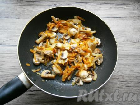 Обжарить овощи до мягкости моркови (ориентировочно в течение 5-6 минут), периодически перемешивая. Шампиньоны (или отваренные лесные грибы) нарезать на части. К обжаренным овощам добавить нарезанные грибы, немного посолить, перемешать и обжаривать в течение 5-7 минут, иногда помешивая. Убрать с огня, дать немного остыть.
