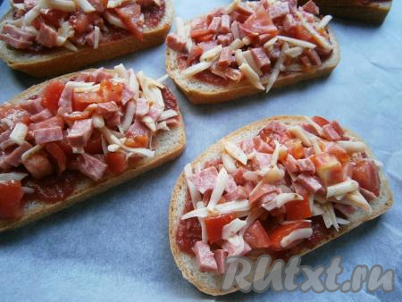 Далее на ломти батона, смазанные соусом, равномерно разложить смесь из колбасы, сыра и помидоров.