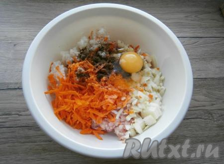 К фаршу, рису и луку добавить натёртую на крупной тёрке очищенную морковь, сырое яйцо, соль и чёрный молотый перец, перемешать.