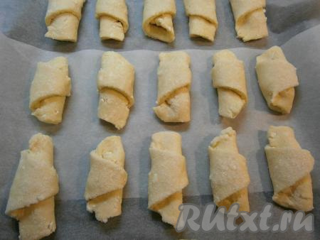 Начиная со стороны с начинкой, свернуть тесто в рулетик, формируя рогалик. Постепенно сформировать все 16 рогаликов из творожного теста с начинкой из варёной сгущёнки. В тарелку всыпать 1 столовую ложку сахара и верх рогаликов обвалять в сахаре. Рогалики на небольшом расстоянии друг от друга выложить на противень, застеленный пергаментом.