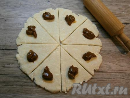 На широкий край каждой части теста, немного отступая от краёв, выложить по 1 чайной ложке варёной сгущёнки.