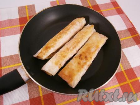 Далее обжарить сосиски в лаваше на сковороде на растительном масле на небольшом огне  до румяности с двух сторон.