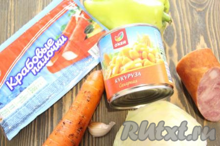 Подготовить продукты для приготовления салата с крабовыми палочками, колбасой, кукурузой и капустой. Если крабовые палочки заморожены, их нужно полностью разморозить.