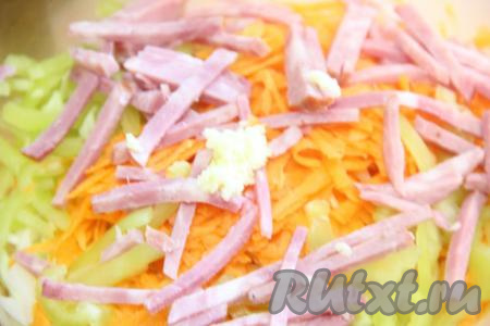 Перец, колбасу и очищенный чеснок, пропущенный через пресс, добавить в салат из капусты и моркови.