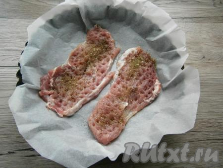 Отбивные посолить и посыпать специями для мяса.&nbsp;Форму для запекания застелить пергаментом (или фольгой). Выложить в форму свиные отбивные.