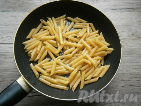 Всыпать в сковороду сухие макароны, перемешать и обжарить с маслом в течение 1-2 минут на среднем огне, помешивая.