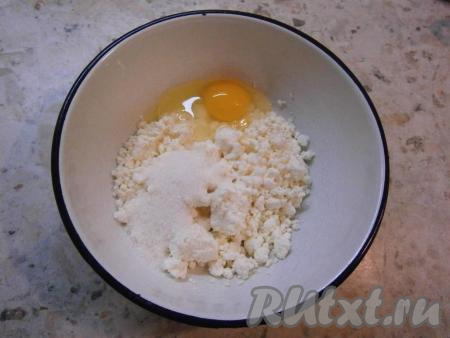 В творог (лучше взять базарный, жирненький) добавить сырое яйцо, щепотку соли, всыпать сахар.
