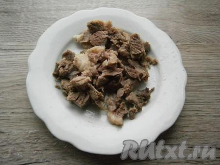 Далее мясо вынуть из бульона, долить воду в кастрюлю, довести до кипения. Мясо остудить и освободить от костей. Крупные части мякоти нарезать.