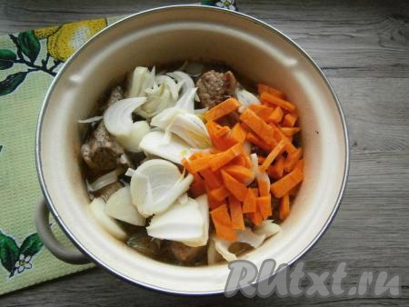 Влить в кастрюлю воду, дать закипеть. Тушить свиные ребра на небольшом огне минут 30 под крышкой, после чего добавить крупно нарезанный репчатый лук и нарезанную брусочками морковь, перемешать и продолжить готовить ещё 10-15 минут.