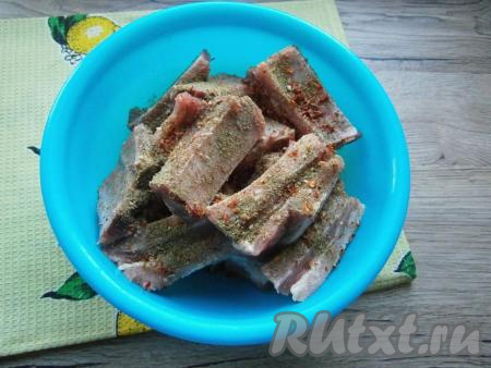 Нарезать ребра по кости на части, посолить, посыпать хлопьями паприки, черным молотым перцем и хмели-сунели, перемешать.