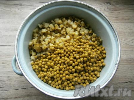 Небольшими кубиками нарезать маринованные огурцы, отжать их от жидкости, добавить в салат вместе с консервированным горошком.
