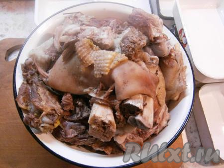 Когда пройдет 4 часа, добавить в кастрюлю нарезанный очищенный чеснок и лавровые листья, варить холодец далее еще минут 30. Все мясо должно с легкостью отставать от костей. Газ выключить, крышку с кастрюли убрать и дать бульону немного остыть и настояться. Затем вынуть из бульона все мясо, остудить его. Сам же бульон процедить.