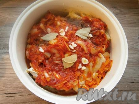 Лук очистить, нарезать кусочками, очищенную морковь натереть на терке, обжарить овощи на сковороде на растительном масле до мягкости, помешивая, затем добавить томатную пасту и 100 мл горячей воды. Подливу посолить по вкусу, добавить немного сахара, протушить минут 5. Вылить подливу на голубцы, также влить еще 300 мл воды. Добавить лавровые листья, немного черного молотого перца и нарезанный очищенный чеснок.