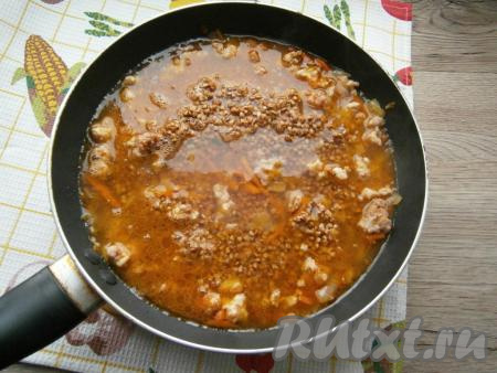 Влить кипяток, добавить перебранную гречневую крупу, перемешать. Накрыть сковороду плотно крышкой.